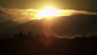 Silhouetted cowboys riding at sunset kicking up dust Shot in slow motion with a lens flare [upl. by Assirt]